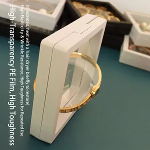 White PE film jewelry display case for floating gold bracelet on green background