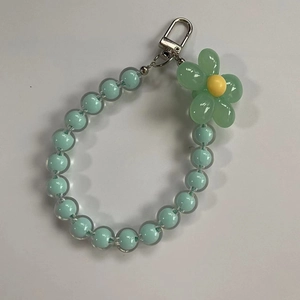 Detailed view of mint green beaded phone strap with a blooming flower charm and silver clasp