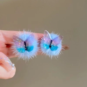 Detail of blue purple plush earrings featuring butterfly wings with glitter decoration