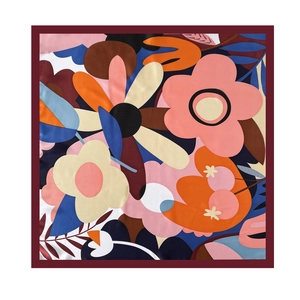 Flat lay detail of a 70cm square silk scarf with vibrant floral patterns and red edges