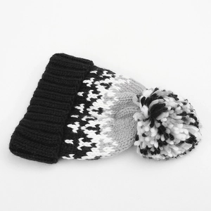 Detailed close-up of geometric knit pattern and soft pom-pom on the winter beanie hat