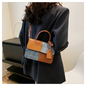 Detail of color-block crossbody bag featuring brown leather and grey-blue suede panels