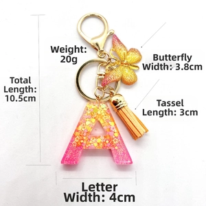 Detail of pink resin letter A keychain with butterfly charm and orange leather tassel