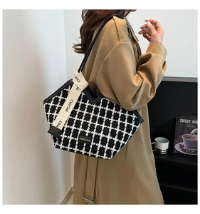 Detail of checkered tote bag showing the wide strap and tweed texture on a model
