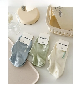 Close-up of three pairs of combed cotton low-cut socks in light blue, green, and cream colors