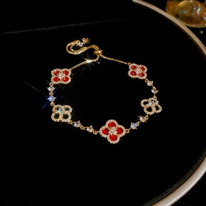 Detail of red clover bracelet with 18k gold plating and sparkling zircon stones on black velvet