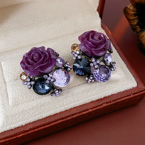 Macro view of vintage flower earrings with purple resin rose and colorful crystals