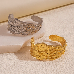 Macro shot of silver and gold wide cuffs with unique irregular crumpled metal textures
