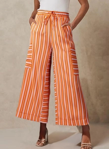 Detail of orange striped wide-leg pants featuring an elastic drawstring waist and large pockets