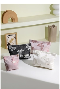Vista dettagliata delle borse da trucco jacquard con fiocchi in nero, rosa e bianco crema