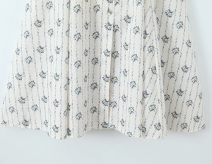 Detailed close-up of blue floral patterns and fabric buttons on an off-white summer dress