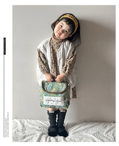 Girl model showing a floral canvas handbag with retro print and white embroidered patch