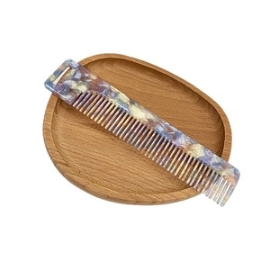 Colorful acetate wide-tooth hair comb with marble texture in a stylish wooden tray