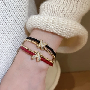 Détail du bracelet en cuir tressé plaqué or avec maillon croisé et pierres de zircon