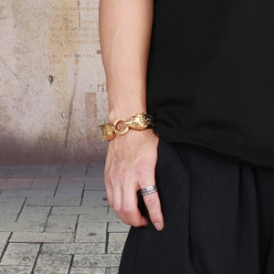 Detail of men's woven leather bracelet with gold wolf heads and vintage silver ring