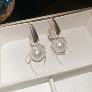 Macro detail of silver pearl earrings with bead chain mesh and fringe design in a jewelry box