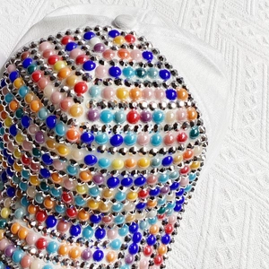Detailed close-up of a white baseball cap with colorful pearls and sparkling rhinestones