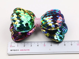 Macro detail of an 8cm sequins bow hair clip with colorful gradient glitter surface