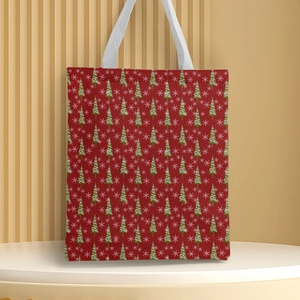 Detail of red Christmas canvas tote bag featuring green tree and white snowflake prints