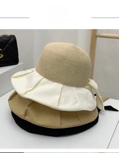 Three wide brim straw sun hats in white, beige, and black with bow detail and pleats