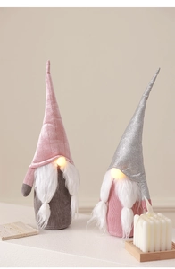 Detail of two plush pink and grey Christmas gnomes with LED glowing noses for home decor