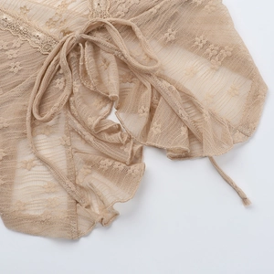 Macro detail of beige lace halter top with intricate hollow embroidery and ruffle hem