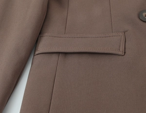 Détail de la veste marron montrant le rabat de la poche et la texture du tissu