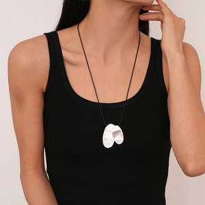 Detail of silver irregular oval pendants on black cord worn by a model in close-up