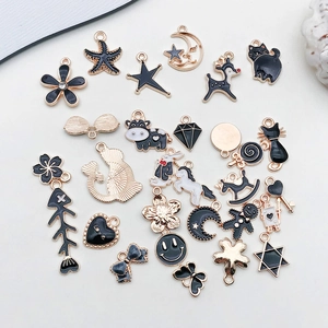 Detailed flat lay of black and gold enamel charms in star, moon, and heart shapes