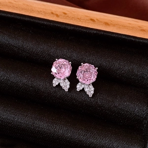 Detailed macro view of pink zircon rose earrings with silver leaf and sparkling accents