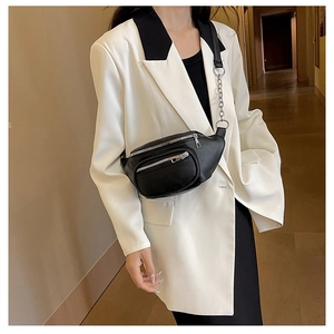 Sac de poitrine en similicuir noir avec chaîne argentée porté sur un blazer blanc chic