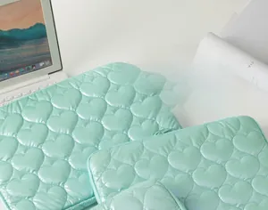 Detail of mint green heart quilted laptop sleeve and pouches with silky texture finish
