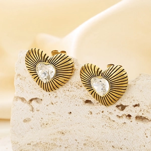 Macro shot of gold heart stud earring with clear crystal and sunburst texture on stone