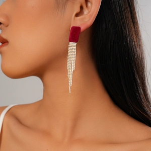 Détail de boucles d'oreilles rouges floquées avec glands en strass portées par un mannequin
