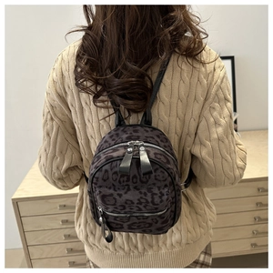 Detailed view of leopard print mini backpack on a model wearing a cable knit sweater