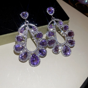 Detailed macro view of silver hollow teardrop earrings with purple stones and diamonds
