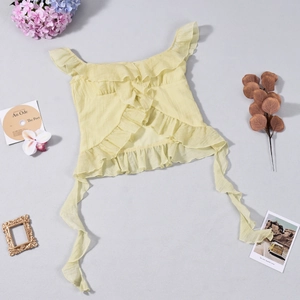 Flat lay of a pale yellow off-shoulder crop top with ruffles and long side ribbons