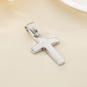 Macro shot of polished silver stainless steel cross pendant on textured fabric