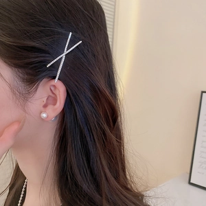 Macro view of a silver crisscross rhinestone hair clip on natural brown wavy hair