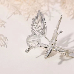 Macro shot of an elegant silver butterfly hair clip with hollow metal wings on dry branches