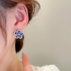 Detail of blue flower stud earring with micro-p鑲zirconia stones on a female model