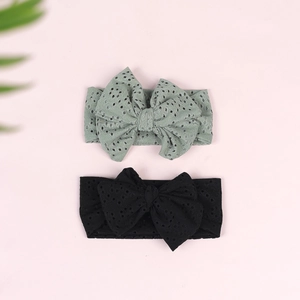 Detail of baby bow headbands in black and sage green with eyelet knit texture