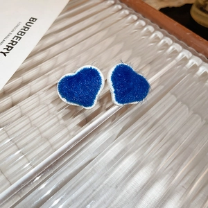 Close-up of blue flocked heart earrings on a glass tray with elegant light reflection