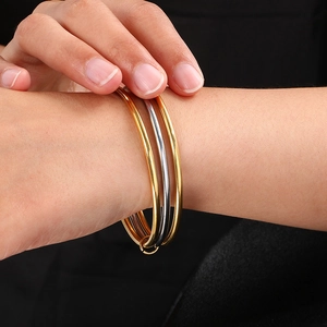 Three interlocking gold and silver stainless steel bangles on model's wrist