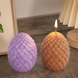 Detalle de velas de huevo de dragón con textura de escamas reales en cera púrpura y naranja