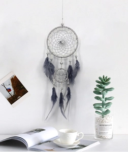 Macro detail of grey dreamcatcher with silver double rings and feathers in room decor