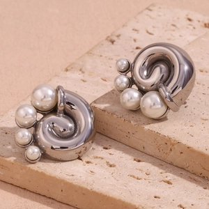Macro shot of silver vintage spiral earrings with white pearls on a stone base