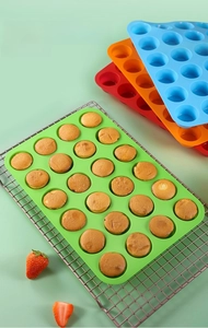 Detail of 24-cup silicone muffin pan with baked cupcakes on a cooling rack
