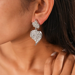 Detailed view of silver wrinkled heart earrings with textured metallic finish on model