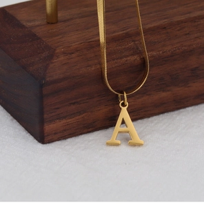Detail of 18K gold plated flat snake chain necklace with an uppercase letter A pendant